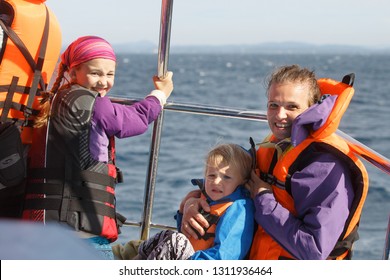 Family On A Blue Whale Watching Trip. Smiling Girl In Safety Jacket On A Boat Trip. Mother Holding Baby.
