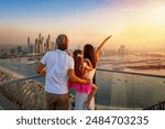 A family on a city vacation trip enjoys the beautiful view of the Dubai Marina district, UAE, during a golden sunset