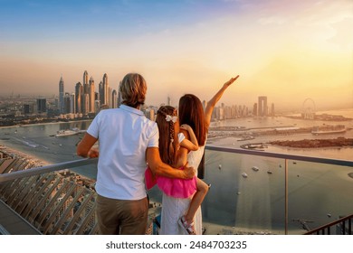 A family on a city vacation trip enjoys the beautiful view of the Dubai Marina district, UAE, during a golden sunset - Powered by Shutterstock