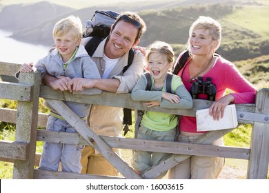 Family on cliffside path leaning on fence and smiling - Powered by Shutterstock