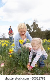 Family On Easter Egg Hunt In Daffodil Field