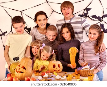 Family On Halloween Party With Children Making Carved Pumpkin.