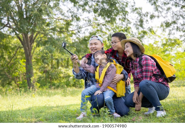 Family on hike in a forest taking selfie\
group portrait.Travel vacations and life\
concept