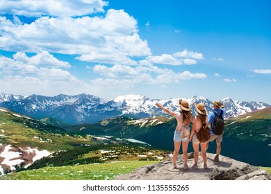 Family On Hiking Trip In The Mountains. Early Summer Landscape With Green Meadows And Snow Covered Mountains.  Trail Ridge Road. Rocky Mountains National Park, Colorado, USA.