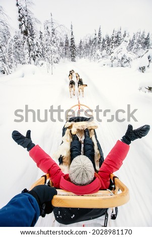Family on husky safari enjoying ride on winter day in Lapland in Finland