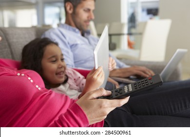 Family On Sofa With Laptop And Digital Tablet Watching TV