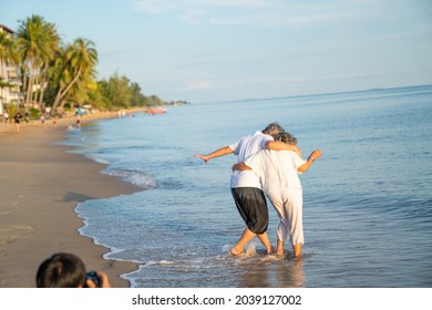 Family On Summer Beach Vacation, Healthy Older Couple Running On Sea Beach, Concept For 
Caring For The Elderly, Caregiving To Older Persons And Relations Of The Family To Support Elderly State