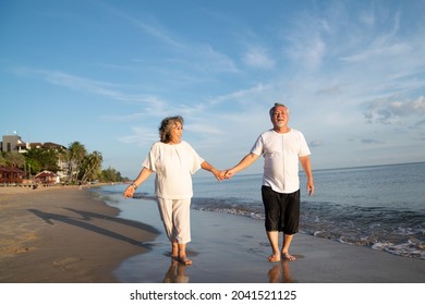 Family On Summer Beach Vacation, Healthy Older Couple Running On Sea Beach, Concept For 
Caring For The Elderly, Caregiving To Older Persons And Relations Of The Family To Support Elderly State