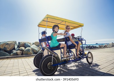 Family On A Surrey Bike Ride Along The Coast Of California