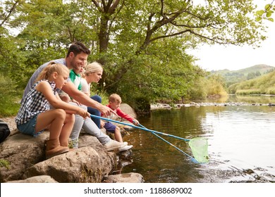 Family On Walk Fishing With Nets In River In UK Lake District