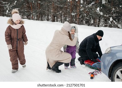 Family On A Weekend In The Snowy Forest, Dad Prepares A Sleigh For Skiing. High Quality Photo