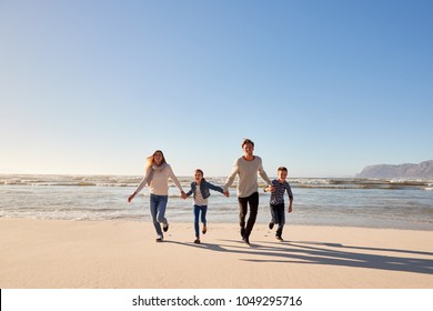 Family On Winter Beach Holding Hands And Running Towards Camera