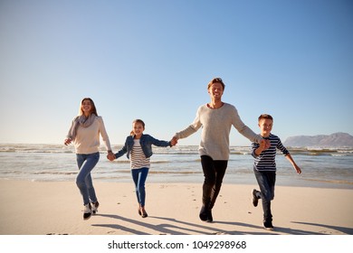 Family On Winter Beach Holding Hands And Running Towards Camera