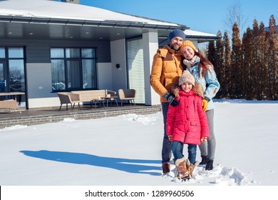 Family On A Winter Vacation Spending Time Together Outdoors Standing Near The House Hugging Looking Camera Smiling Cheerful