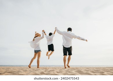 Family outdoor activities, Back family mother, father and son holding hands and jumping in air at dawn time, Happy Asian family people have fun together on beach on holiday summer vacation travel - Powered by Shutterstock