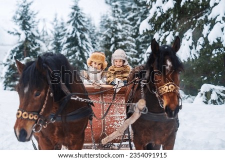 Family outings on horseback and sleigh rides. Two happy children are riding on a horse-drawn carriage. Merry Christmas and Happy New Year greeting card.