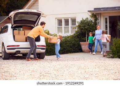 Family Outside New Home On Moving Day Loading Or Unloading Boxes From Car