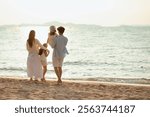 family, parent, children, kid, kids, parents, relaxed, together, child, togetherness. A family of four is walking on the beach, with a baby being carried by a man. The scene is peaceful and relaxing.