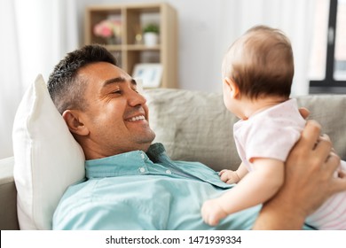 Family, Parenthood And Fatherhood Concept - Happy Smiling Middle Aged Father With Little Baby Daughter Lying On Sofa At Home