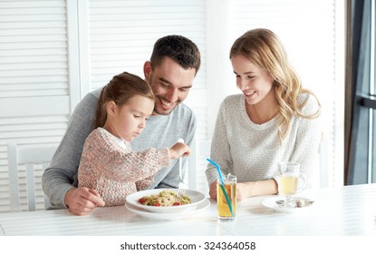 Family, Parenthood, Food And People Concept - Happy Mother, Father And Little Girl Eating Pasta For Dinner At Restaurant Or Cafe