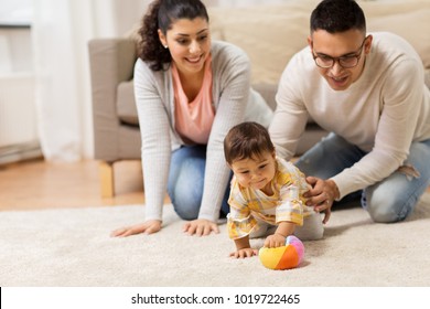 Family, Parenthood And People Concept - Happy Mother, Father And Baby Daugter Playing With Ball At Home