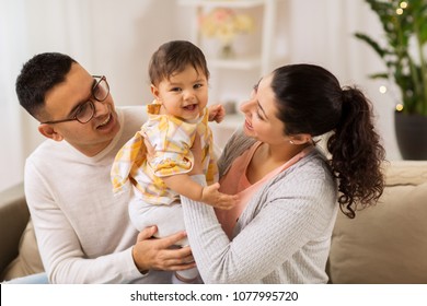 family, parenthood and people concept - happy mother, father with baby daughter at home