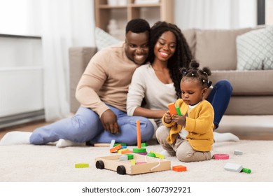 Family, Parenthood And People Concept - Happy African American Mother, Father And Baby Daughter Playing With Toy Blocks At Home