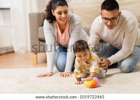 family, parenthood and people concept - happy mother, father and baby daugter playing with ball at home