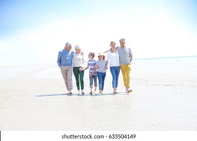 Family, parents, grandparents and grandkids walking on the beach - Powered by Shutterstock