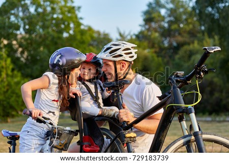 Family in park riding bicycles. Two girls ride biked with their father