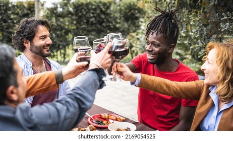 Family Party With Adoptive Parents And Children To Celebrate The Achievements Of The Young Student Of African Descent, Mixed Age Range People Toasting With Red Wine Glasses At Barbecue