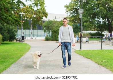 Family, Pet, Animal And People Concept - Happy Man With Labrador Retriever Dog Walking In City Park