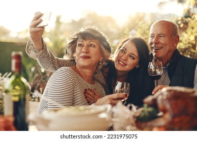 Family, phone selfie and happy thanksgiving, lunch and happy with wine, glass and social media photo in home. Senior mother, father and daughter smile, love and together for picture, alcohol and care - Powered by Shutterstock