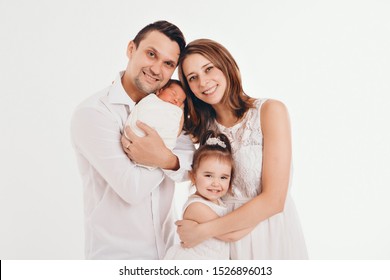 Family Photo On A White Background: Parents Spend Time With Their Children. Mom And Dad Hug The Baby. The Concept Of Childhood, Fatherhood, Motherhood, IVF