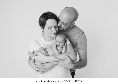 Family Photo On A White Background: Parents Spend Time With Their Children. Mom And Dad Hug The Baby. The Concept Of Childhood, Fatherhood, Motherhood, IVF