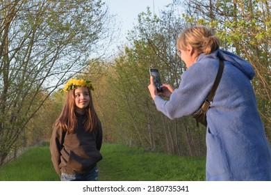 Family Photography At Sunset In The Forest. Mom Takes A Picture Of Her Daughter On A Smartphone In Nature