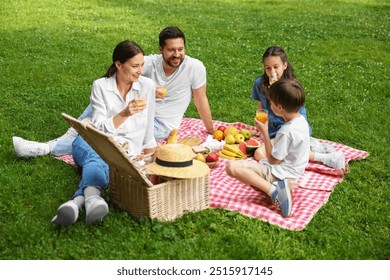 Family picnic. Happy parents and their children drinking juice on green grass outdoors - Powered by Shutterstock