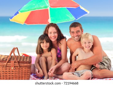 Family Picnicking Under A Sol Umbrella On The Beach