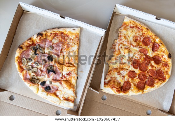 Family pizza, oval, divided into two halves,
consists of three types, margarita, pepperoni, prosciutto fungi.
Food delivery concept, takeaway, Italian cuisine, fast food. Top
view, flat lay,
close-up.