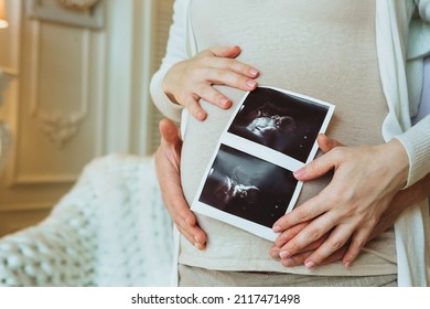 Family Planning. Cropped Shot Of Loving Husband Hugging His Pregnant Wife Holding Ultrasound Scan In Hands, Man And Woman In Anticipation Of Waiting For New Baby At Home. Pregnancy Concept