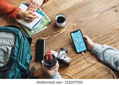 Family planning vacation trip. Girl searching travel destination and routes using navigation map on mobile phone. Woman writing journal and making notes. Charging smartphone with power bank - Powered by Shutterstock