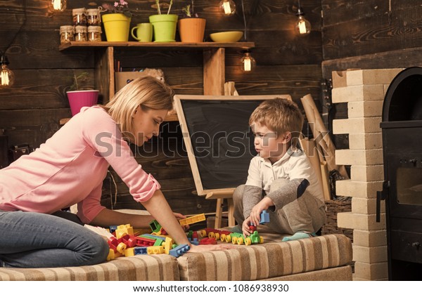 Family play with constructor at home. Mom\
and child play with details of constructor, plastic bricks.\
Motherhood concept. Nursery with chalkboard on background. Mother\
and son play with\
constructor.