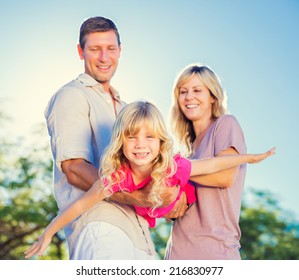 Family Playing Airplane With Young Daughter On The Beach