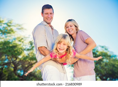 Family Playing Airplane With Young Daughter On The Beach