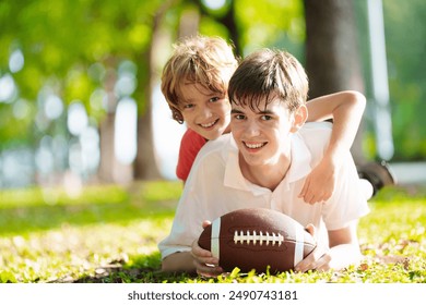 Family playing American football. Kids play rugby in sunny summer park. Father and children throw ball, run and laugh. Healthy outdoor sport activity. - Powered by Shutterstock