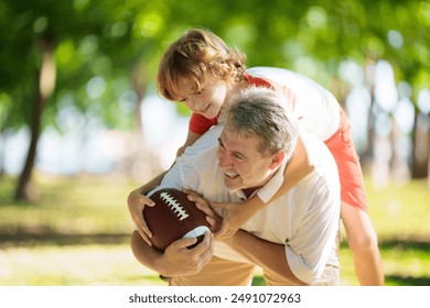 Family playing American football. Kids play rugby in sunny summer park. Father and children throw ball, run and laugh. Healthy outdoor sport activity. - Powered by Shutterstock