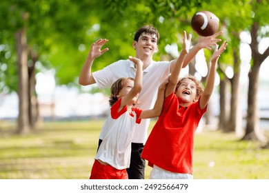 Family playing American football. Kids play rugby in sunny summer park. Father and children throw ball, run and laugh. Healthy outdoor sport activity. - Powered by Shutterstock