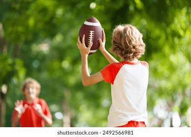 Family playing American football. Kids play rugby in sunny summer park. Father and children throw ball, run and laugh. Healthy outdoor sport activity. - Powered by Shutterstock