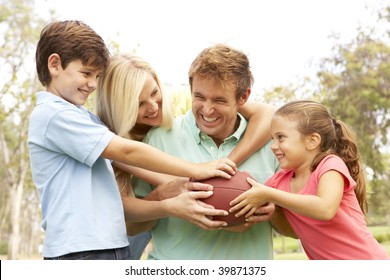 Family Playing American Football Together In Park