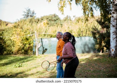 Family Playing Badminton Outdoors In Green Backyard